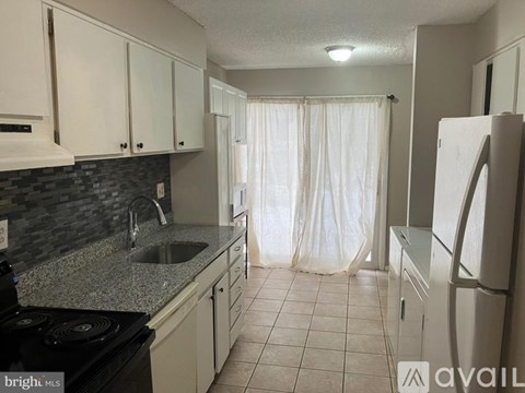 A kitchen with white cabinets and a black stove top oven.