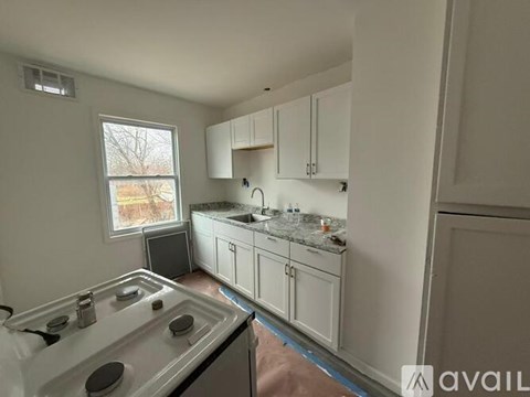 A kitchen with white cabinets and a window showing bare trees outside.