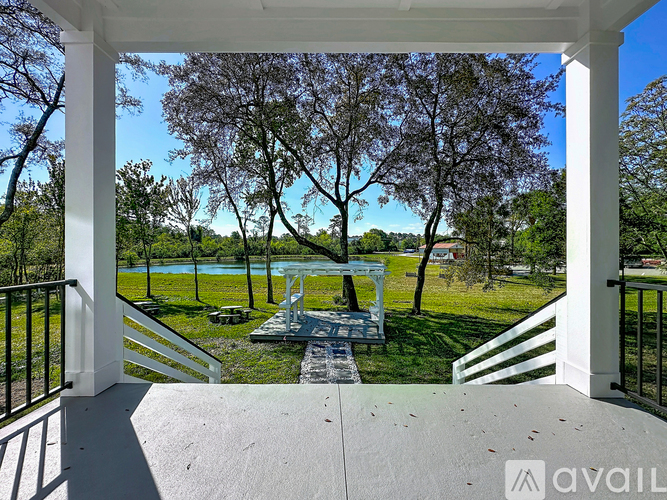 A white gazebo is situated on a patio with a view of a pool and trees.
