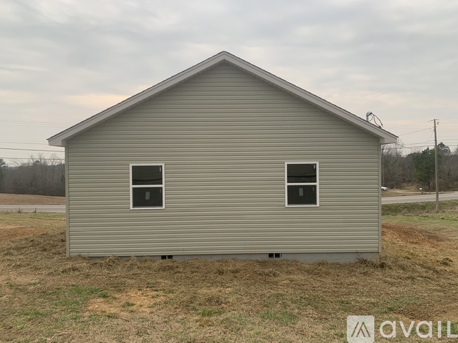 A small, grey house with two windows is available for purchase.
