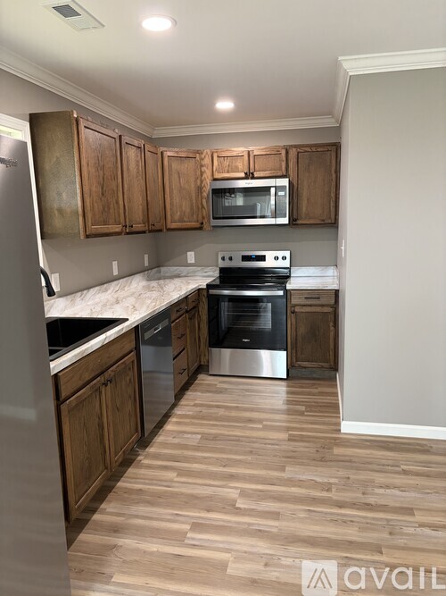 A kitchen with wooden cabinets and a stainless steel refrigerator.