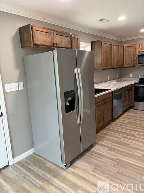 A stainless steel refrigerator in a kitchen with wooden cabinets.