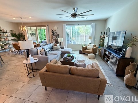 A living room with a brown couch and a ceiling fan.