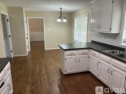 A kitchen with white cabinets and a black countertop.
