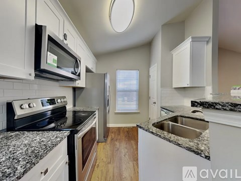 A kitchen with granite countertops and white cabinets.