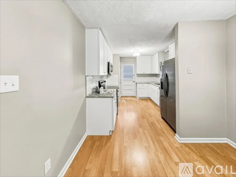 A kitchen with white cabinets and a wooden floor.