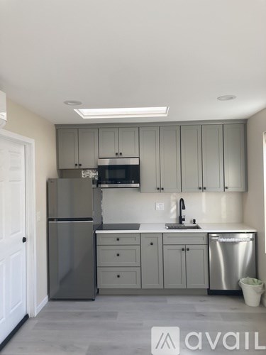 A kitchen with a refrigerator, microwave, and dishwasher.
