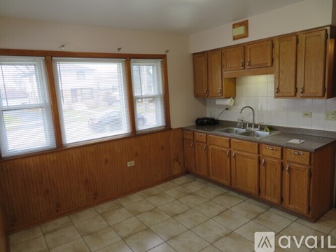 A kitchen with wooden cabinets and a tiled floor.