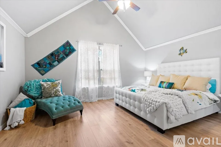 A bedroom with a white bed and a green bench.