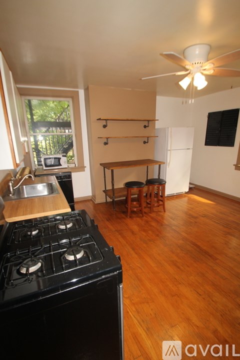 A kitchen with a black stove top and wooden floors.