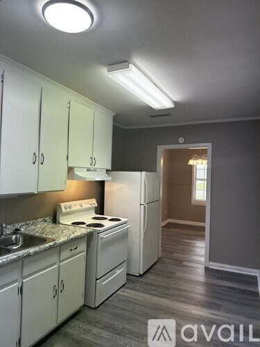 A kitchen with white cabinets and a white fridge.
