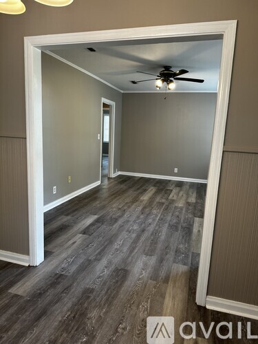 A room with a ceiling fan and wooden flooring.
