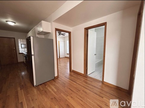 A kitchen with a refrigerator and wooden floors.