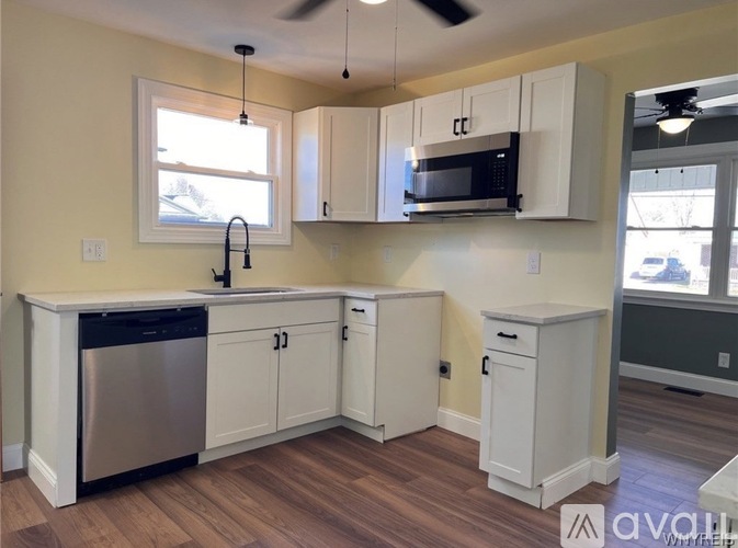 A kitchen with white cabinets and a black microwave.