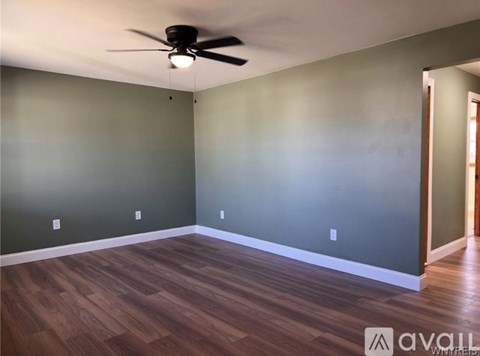 A room with a ceiling fan and wooden flooring.