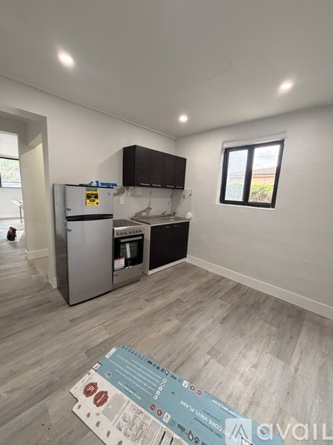 A kitchen with a fridge, oven, and microwave in a room with a window.