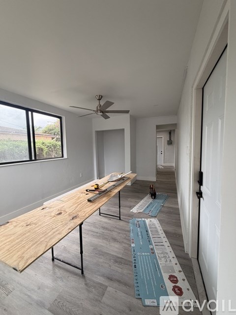 A room with a long wooden table and a ceiling fan.