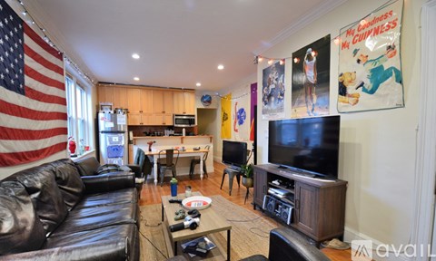 A living room with a black leather couch and an American flag on the wall.