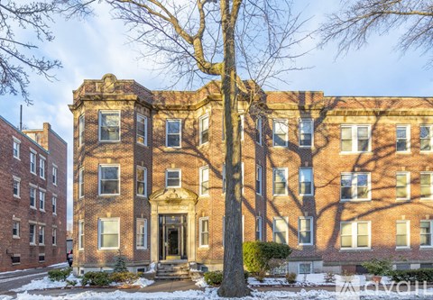 A large red brick building with a tree in front.