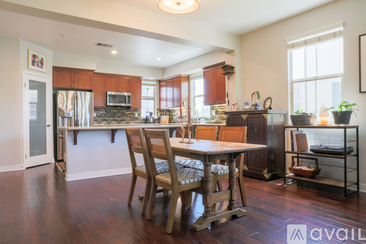 A kitchen with wooden floors and a dining table with chairs.