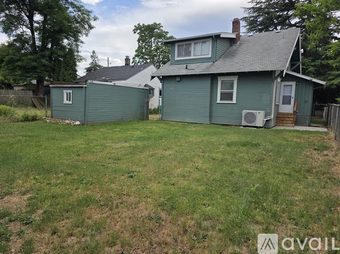 A house with a green lawn and trees in the background.
