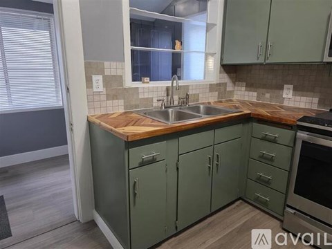 A kitchen with green cabinets and a wooden countertop.