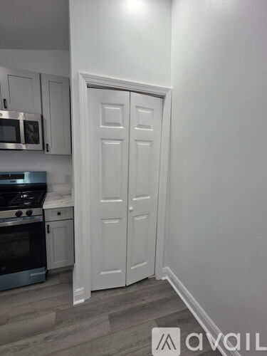 A white door is in a room with a stove and microwave.