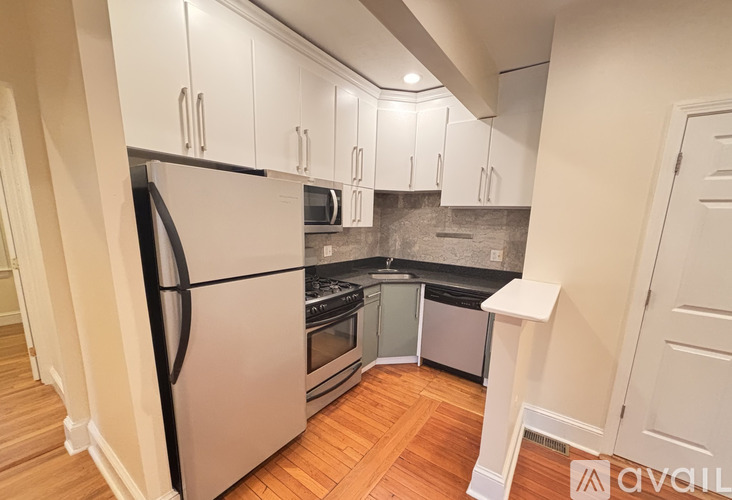 A kitchen with white cabinets and a stainless steel refrigerator.