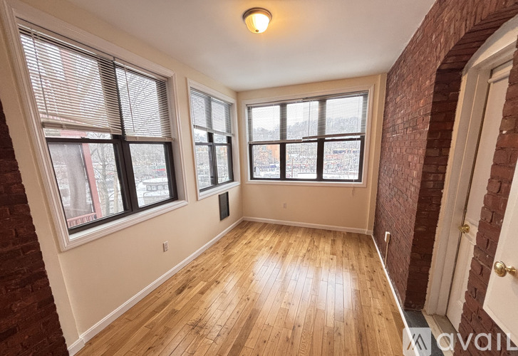 A room with wooden floors and three windows.
