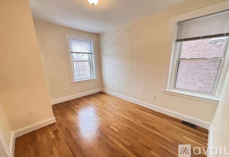 A room with wooden floors and a window showing a view of a building outside.