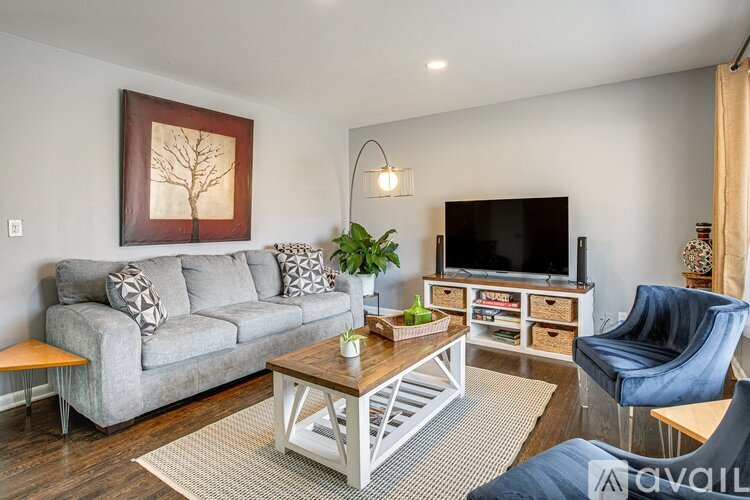 A living room with a grey couch, a coffee table, a TV, and a plant.