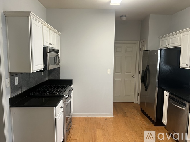 A kitchen with white cabinets and black countertops.