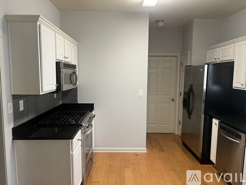 A kitchen with white cabinets and black countertops.