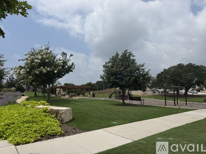 A park with a walking path, benches, and trees.
