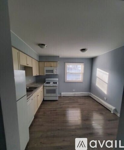 A kitchen with white appliances and wooden floors.