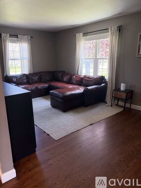 A living room with a brown leather couch and a rug.