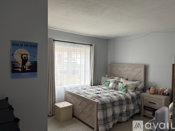 A poster of Kevin Costner as "Head of the Kevin" hangs on the wall above a bed in a bedroom.