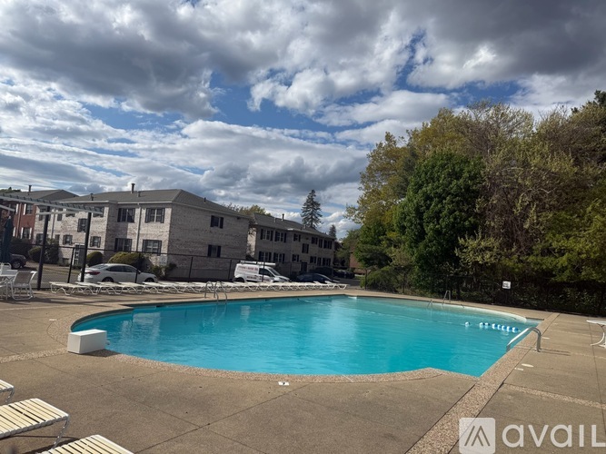 A swimming pool surrounded by a concrete deck and apartment buildings.