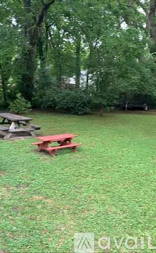 A picnic table sits on a grassy area with trees in the background.