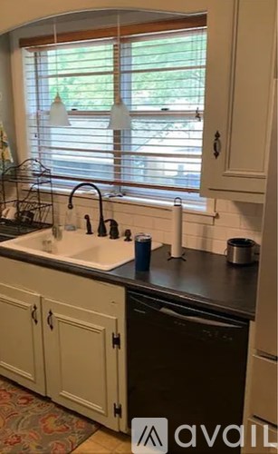 A kitchen with a sink and a window with blinds.