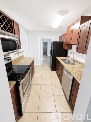 A kitchen with brown cabinets and a black refrigerator.