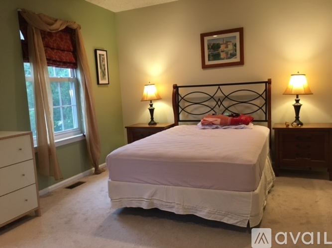 A bedroom with a white bed and two lamps on either side of the bed.
