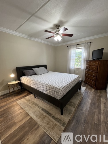 A bedroom with a bed, dresser, and ceiling fan.