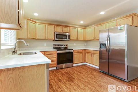 A kitchen with wooden cabinets and a stainless steel refrigerator.