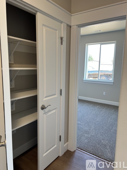 A white pantry with a door open to a living room.