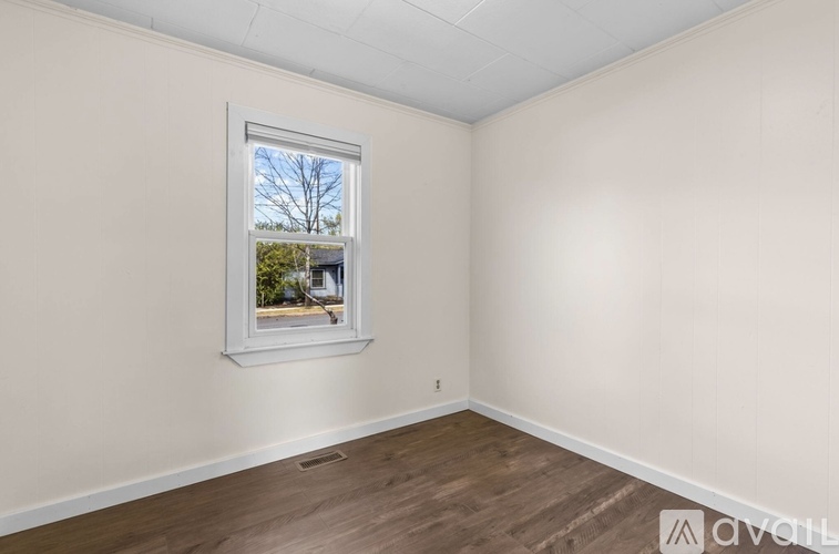 A room with a window showing a tree and a building outside.