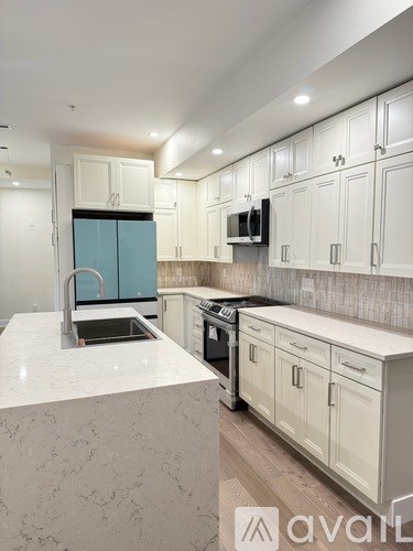 A kitchen with white cabinets and a marble countertop.