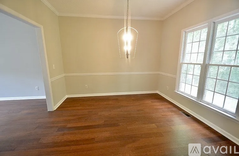 A room with wooden floors and a window with a view of trees.