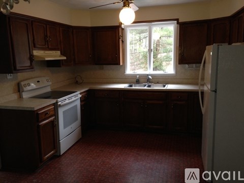 A kitchen with dark wood cabinets and a white stove top oven.