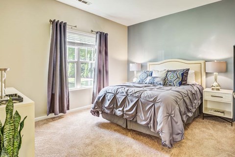 A bedroom with a bed, nightstand, and window.